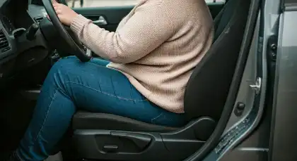 conductor con sobrepeso al que el volante casi le golpea las piernas