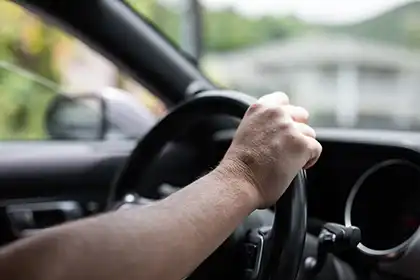 conductor que sujeta el volante con una sola mano