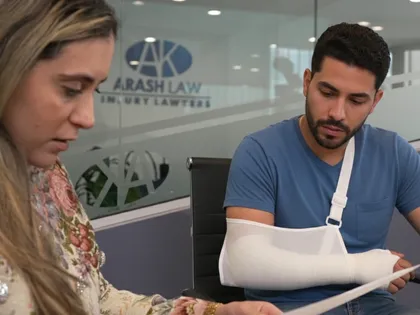 Un hombre herido, con el brazo en cabestrillo, consulta con un abogado en un bufete tras un accidente de coche.