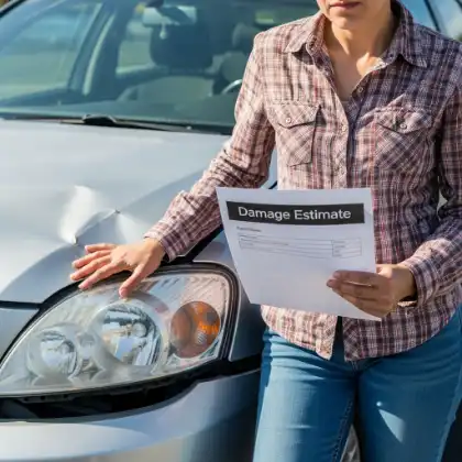 mujer con un coche siniestrado revisando las estimaciones de daños de la compañía de seguros