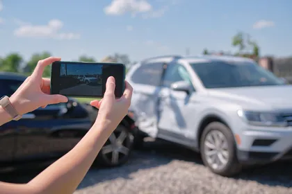 Car accident scene showing a person photographing damaged vehicles to preserve evidence for an auto insurance claim