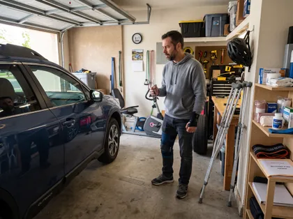 Car accident victim with knee and wrist injuries standing beside a vehicle while recovering