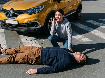 Pedestrian accident victim lying on a crosswalk while a distressed woman calls emergency services