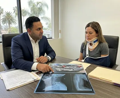 Personal injury attorney explaining car crash case details using X-rays and accident photos to injured client