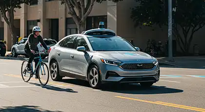 Un coche autónomo que comparte la carretera con un ciclista en un entorno urbano en un día despejado