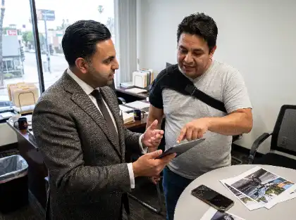 Injured driver wearing a shoulder brace reviewing car accident evidence with an attorney in an office
