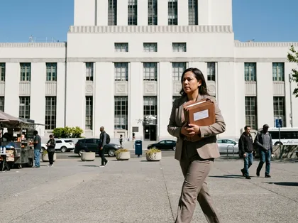 Legal professional walking with case documents near an Alameda government building