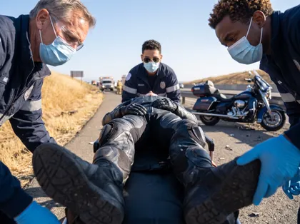 Paramedics treating an injured motorcyclist on a stretcher after a motorcycle accident on a highway