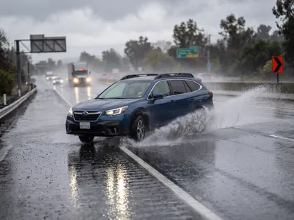 Un coche circulando bajo una lluvia intensa por una autopista mojada de California