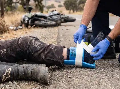 Un miembro del equipo de emergencias inmovilizando el tobillo de un motorista tras una lesión sufrida en un accidente de moto