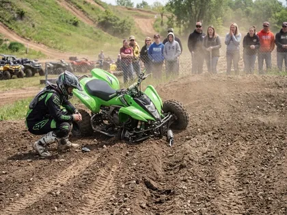 Un piloto de quad inspecciona un quad volcado tras un accidente en una pista de tierra durante una prueba de motor todoterreno