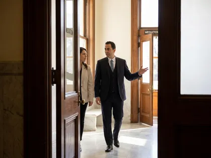Abogado profesional que acompaña a un cliente durante una mediación en el juzgado, mientras le explica las opciones legales y los siguientes pasos a seguir