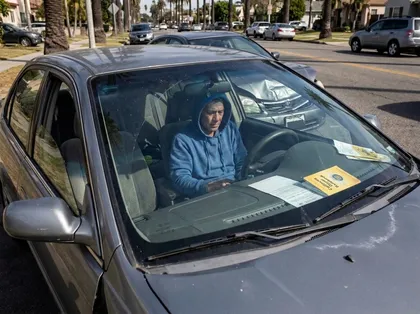 Distracted driver looking down inside a vehicle on a busy Los Angeles road