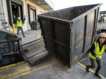 Worker moving away from a large industrial container shifting at a loading dock
