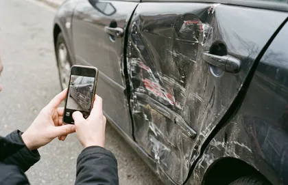 Car accident victim photographing vehicle damage before settling a property damage claim