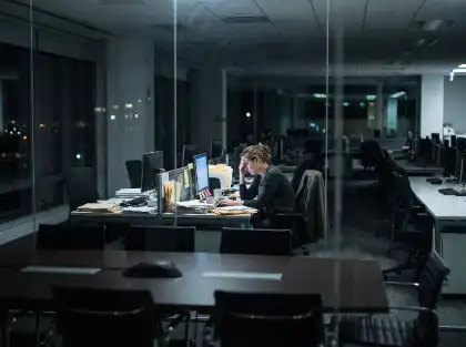 Exhausted employee working late in a dark office