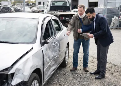 Tow truck accident lawyer inspecting vehicle damage with an injured client during a crash investigation
