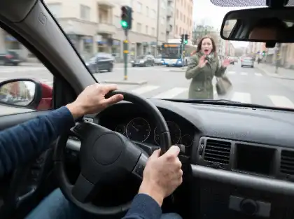 Woman raising her hands in surprise at a San Francisco crosswalk from a driver’s view